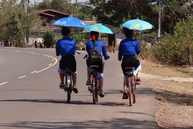 filles à vélos avec parapluie pour se protéger du soleil