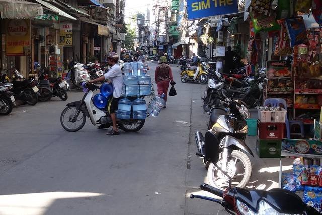 Scooter transportant plusieurs bonbonnes d'eau