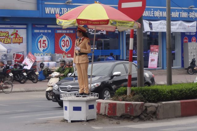 Agent de circulation, sous un parasol à Ninh Binh